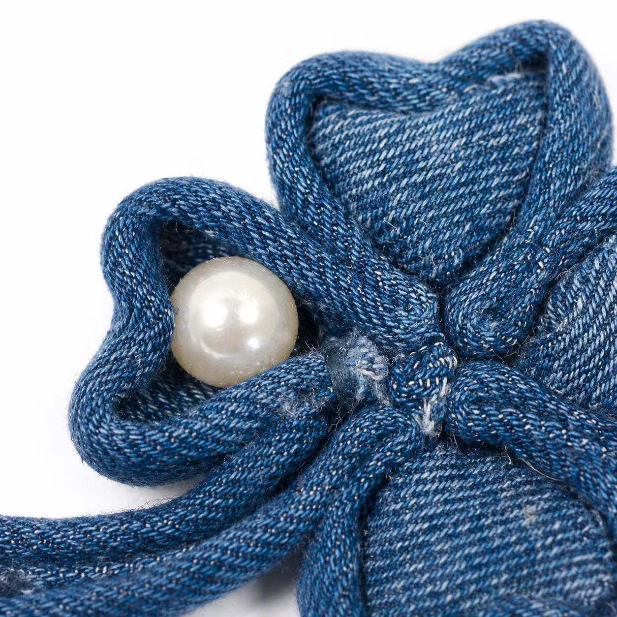 Close-up of the denim textile brooch with pearl detail